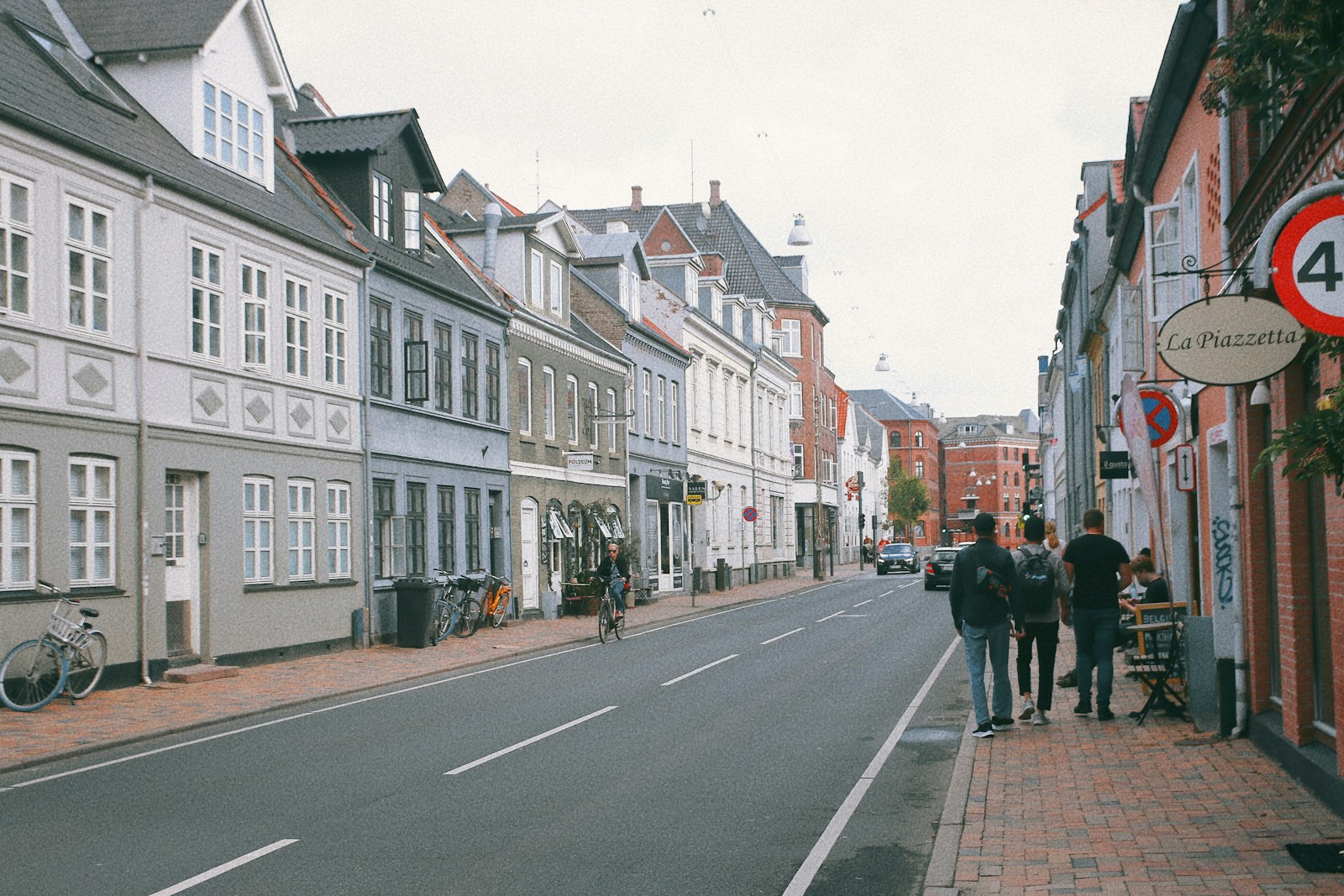 a group of people walking down a street next to tall buildings